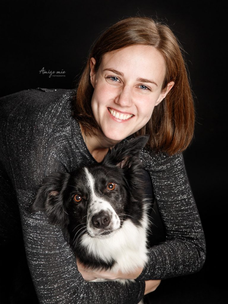 Chica abrazando su cachorro bordercollie en un fondo negro