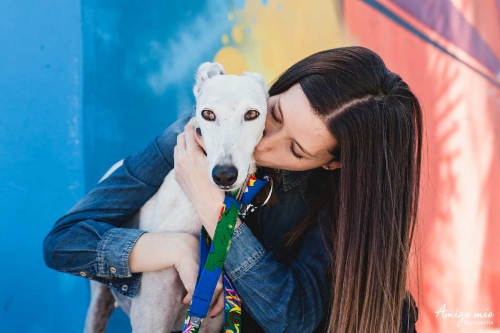 chica abrazando a su galga blanca con una pared de graffiti