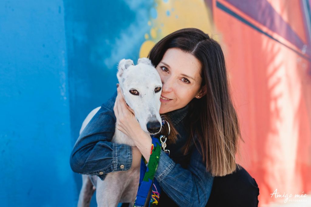 chica abrazando a su perrita adelante de un graffiti