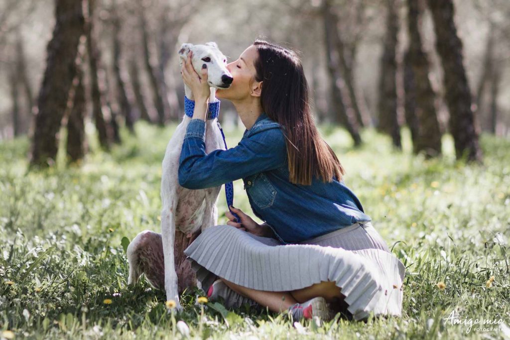 una chica da un beso a su galga blanca en un parque de madrid